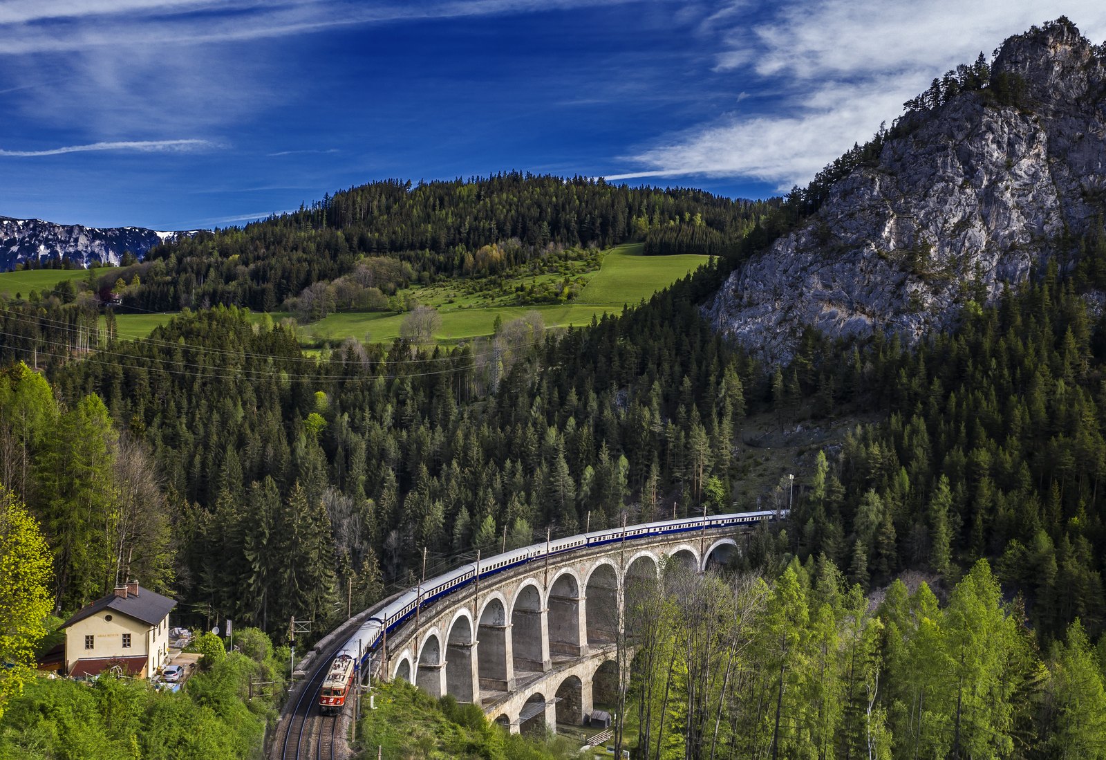 Golden Eagle Danube Express crossing a stone viaduct through forested mountains